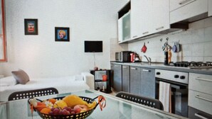 Een moderne keuken met roestvrijstalen apparatuur, een eethoek met een glazen tafel en een fruitschaal op tafel.