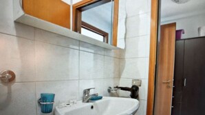 Een badkamer met een witte wastafel, een spiegel en een raam.