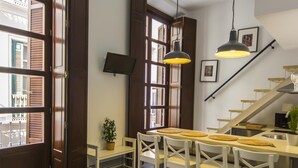 Eine moderne Küche mit Essbereich, Holzklappläden, einem Topf mit Pflanze und einer Treppe.