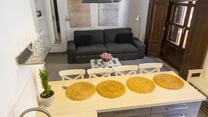 Eine moderne Küche mit Essbereich, ausgestattet mit einem grauen Sofa, einem Couchtisch mit einer Vase und einer hängenden Pendelleuchte.
