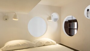 Ein Schlafzimmer mit einem Bett, zwei wandmontierten runden Spiegeln und einem weiteren Spiegel an der Wand.