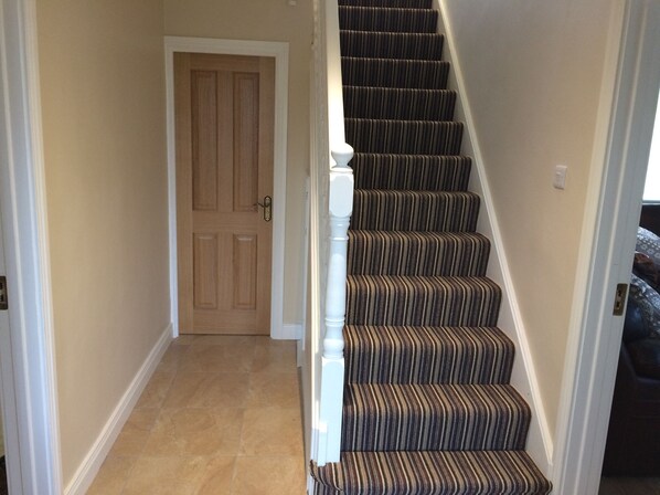 A staircase with striped carpet and white balusters, leading to a wooden door. - Greenridge House, Ring of Gullion, Co. Armagh (Crossmaglen)