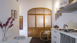 A kitchen with a dining table set, a wicker chair, and a kitchen counter with a kettle. - GuestHost - 55 sqm apartment for 4 people, located on the 1st floor (no elevator) of a historic building in the lively San Lorenzo district of Florence. Just a short distance from the famous market and the station, with a view of the Basilica of San Lore (Firenze)
