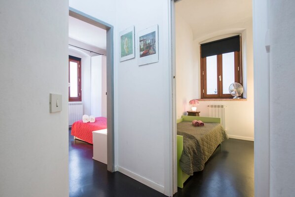 A bedroom with a bed, a bedside table, a window, and a radiator.