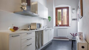 A kitchen with white cabinets, a stainless steel range hood, a window with shutters, and a radiator. - GuestHost - 55 sqm apartment for 4 people, located on the 1st floor (no elevator) of a historic building in the lively San Lorenzo district of Florence. Just a short distance from the famous market and the station, with a view of the Basilica of San Lore (Firenze)