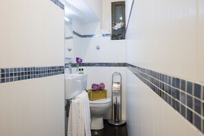 A compact bathroom with a toilet, bidet, and a small sink.