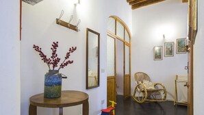 A hallway with a round wooden table, a wicker rocking chair, a small child's toy, and framed pictures on the wall. - GuestHost - 55 sqm apartment for 4 people, located on the 1st floor (no elevator) of a historic building in the lively San Lorenzo district of Florence. Just a short distance from the famous market and the station, with a view of the Basilica of San Lore (Firenze)