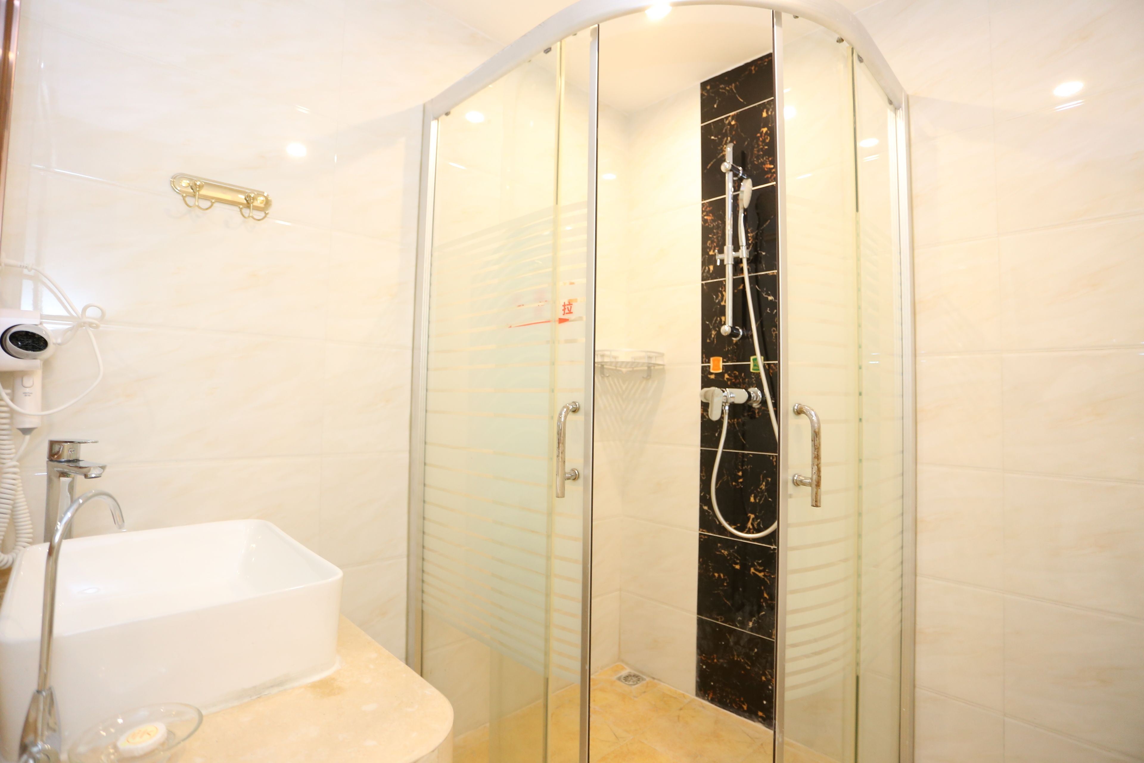A modern bathroom with a glass-enclosed shower, a white sink, and a handheld showerhead.