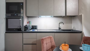 Une cuisine moderne équipée d’un four à micro-ondes, d’un four traditionnel et d’un évier, ainsi qu’un coin repas avec une table et des chaises.