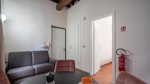 Une pièce avec un canapé, une table sur laquelle se trouvent une tasse et une cafetière, et un extincteur accroché au mur.