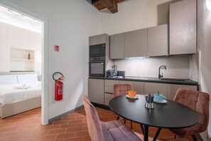 A compact kitchen with modern appliances, a dining area with two chairs, and a visible fire extinguisher.