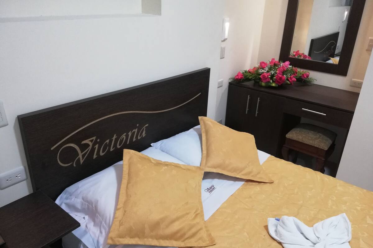 Una cama bien hecha con cabecera identificada con el nombre 