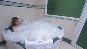 Una bañera llena de burbujas, una toalla y un letrero que indica el uso de un jabón específico.