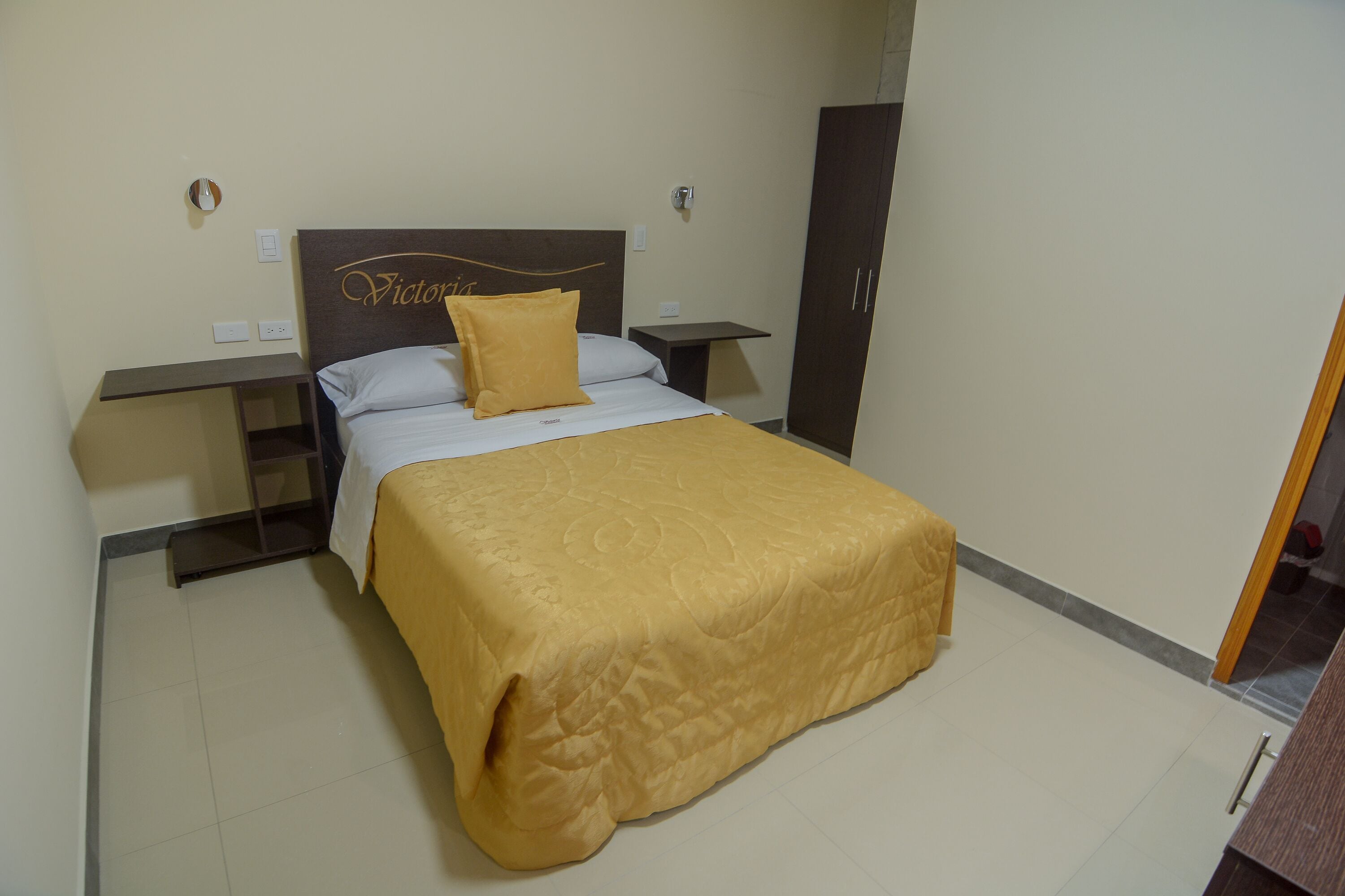 Ein Hotelzimmer mit Bett, Nachttisch, Kleiderschrank und kleinem Tisch.