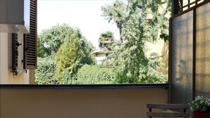 Un balcon donnant sur des arbres et un immeuble.