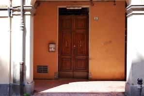 A wooden double door with a number plaque, a vent, and a small sign on the wall.