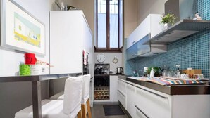 A modern kitchen with white cabinets, a stainless steel countertop, a window with a view, and a clock on the wall. - GuestHost - Stylish Apt w/king size bed M1 Porta Venezia (Milan)