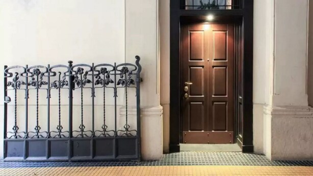 A building entrance with a dark wooden door, a metal gate with intricate designs, and a tiled floor. - GuestHost - Stylish Apt w/king size bed M1 Porta Venezia (Milan)