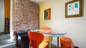 A room with a brick wall, a glass table, orange chairs, and a framed picture on the wall. - GuestHost - Stylish Apt w/king size bed M1 Porta Venezia (Milan)