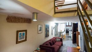 A living room with a sofa, a staircase, and a kitchen in the background. - GuestHost - Stylish Apt w/king size bed M1 Porta Venezia (Milan)