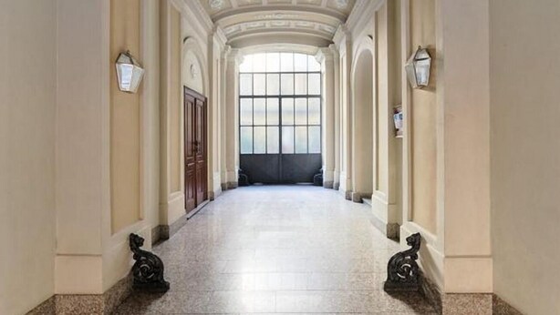 A hallway with a high ceiling, columns, and a large window at the end. - GuestHost - Cozy and stylish studio situated in the centre of Turin in a beautiful historical building with elevator. It is the ideal solution for both short business or leisure stays: the area has a good infrastructure and is well served by lots of faci (Turin)