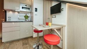 A compact kitchen with modern appliances, a small dining table, and a stool. - GuestHost - Cozy and stylish studio situated in the centre of Turin in a beautiful historical building with elevator. It is the ideal solution for both short business or leisure stays: the area has a good infrastructure and is well served by lots of faci (Turin)