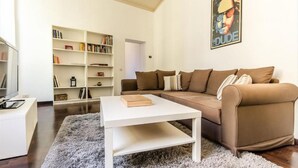 Un salon avec un canapé marron, une table basse blanche et une bibliothèque.