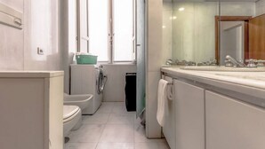 Une petite salle de bain comprenant des toilettes, un lave-linge et un lavabo.