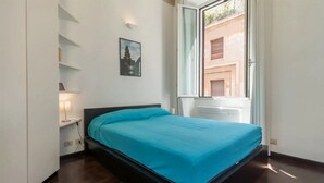 Une chambre à coucher avec un lit, une fenêtre, une étagère fixée au mur et un tableau.