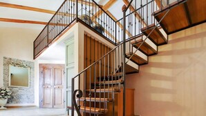 Una escalera de caracol con escalones de madera y barandillas de metal, que sube a un piso superior.
