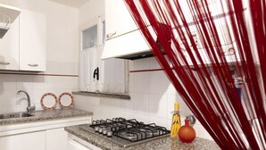 A kitchen with white cabinets, a stainless steel sink, a gas stove, and a red curtain partially covering the view. - GuestHost - Cozy two-room apartment - Piazza della Signoria! NEW (Firenze)