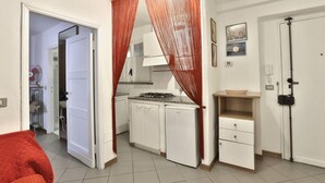 A compact kitchen with white cabinets, a gas stove, and a small refrigerator. - GuestHost - Cozy two-room apartment - Piazza della Signoria! NEW (Firenze)