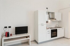 Une cuisine moderne avec des meubles blancs, un four encastré et un four à micro-ondes.