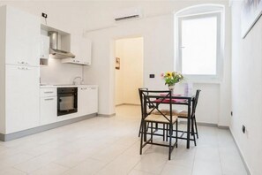 Eine moderne Küche mit weißen Schränken, einem eingebauten Ofen und einem Essbereich mit Tisch und Stühlen.