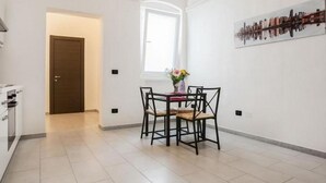 Een moderne keuken met witte kastjes, een eethoek met tafel en stoelen, en een raam met uitzicht.