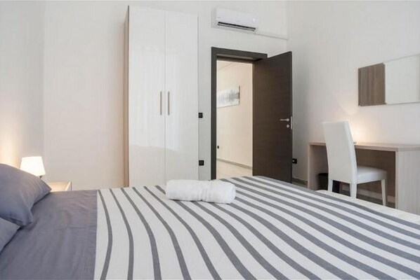 Una habitación de hotel con cama, escritorio, silla y armario.