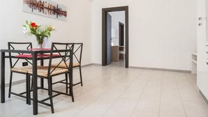 Een eetruimte met een tafel en stoelen, een vaas met bloemen en een stadsgezicht aan de muur.