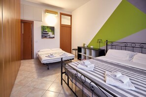 A hotel room with two beds, a wooden wardrobe, a small table with a lamp, and a green and white wall. - GuestHost - NEW! Two-room apartment Tortona Design, Navigli, P.ta Genova (Milano)