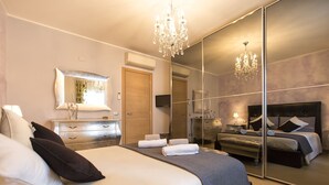 A bedroom with a large bed, a dresser, a mirror, and a chandelier. - ClickSardegna Villa Paradiso with swimming pool and exclusive tennis court (Alghero)