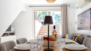 A dining area with a table set for four, a bowl of fruit, and a bottle of wine. - ClickSardegna Villa Paradiso with swimming pool and exclusive tennis court (Alghero)