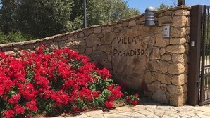 A stone wall with "VILLA PARADISO" written on it, a metal gate, and a bed of red flowers. - ClickSardegna Villa Paradiso with swimming pool and exclusive tennis court (Alghero)