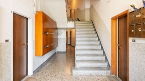 A hallway with a staircase, wooden doors, and a mail slot. - GuestHost - Casa Panigale Comfortable Apartment x4! NEW (Bologna)