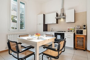Une cuisine moderne avec des meubles blancs, une table à manger avec quatre chaises, une cuisinière encastrée et un four à micro-ondes.