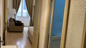 Ein Hotelzimmer mit Bett, Sofa, Lampe und Blick ins Freie.