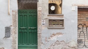 Ein Gebäude mit einer grünen Tür, einem Fenster mit schmiedeeisernem Gitter und einem an der Wand befestigten Stromkasten.