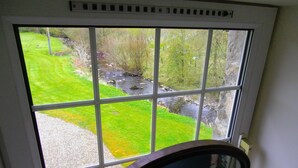 A view through a window with a view of a grassy area and a stream. - Escape to Rural Highlands Stunning Scenery, Sound of the Burn  Licence PK11943F (Aberfeldy)