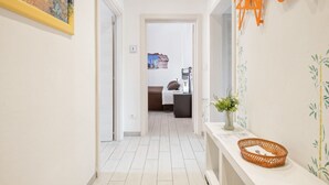 A hallway with a bed, a nightstand, and a vase with flowers. - GuestHost - Large, bright and well-kept apartment on the third floor of a building near the Maggiore Hospital. The historic center is easily accessible by public transport.The apartment, ideal for 5 people, is fully equipped and has 24h WiFi, A / C and h (Bologna)