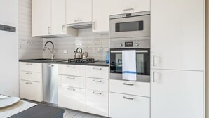 A modern kitchen with white cabinets, stainless steel appliances, and a black countertop. - GuestHost - Large, bright and well-kept apartment on the third floor of a building near the Maggiore Hospital. The historic center is easily accessible by public transport.The apartment, ideal for 5 people, is fully equipped and has 24h WiFi, A / C and h (Bologna)