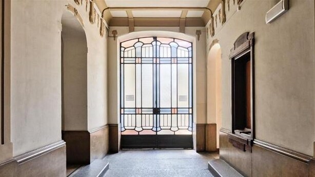 Un pasillo que conduce a una puerta grande y ornamentada con un diseño geométrico.