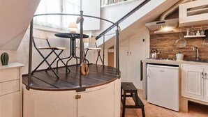 Una cocina con estufa integrada, armarios blancos y un refrigerador pequeño.